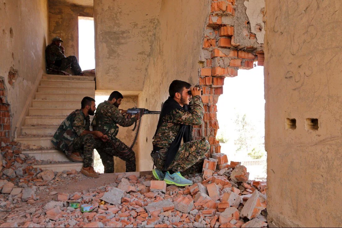 Kurdish People’s Protection Units fighters take up positions inside a damaged building in al-Vilat al-Homor, as they monitor the movements of Islamic State fighters who are stationed in Ghwayran
